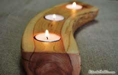 three lit candles sit on top of a wooden object