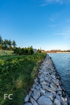 there is a long stone wall next to the water and grass on both sides of it