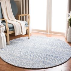 a living room with a blue chair and rug on the floor next to a window