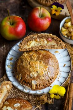 an apple pie on a plate with apples and cinnamon sticks next to it, along with other baked goods