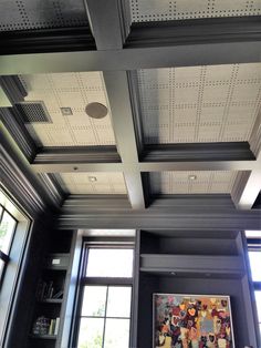 a living room filled with lots of windows next to a ceiling covered in metal grates