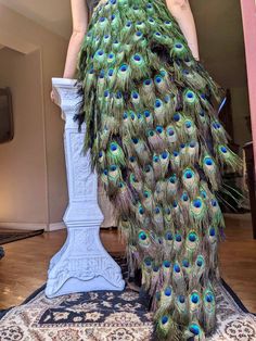 a woman in a dress made out of peacock feathers