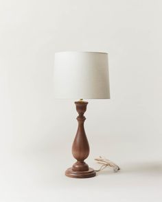 a small wooden table lamp with a white shade on the base and a rope attached to it