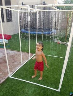 a little boy standing in front of a soccer goal on top of green grass next to a house