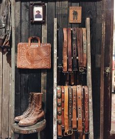 an assortment of leather items on display in a store window with a wooden wall behind it