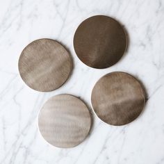 three metal discs sitting on top of a white marble counter