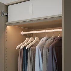 an open closet with clothes hanging on hangers