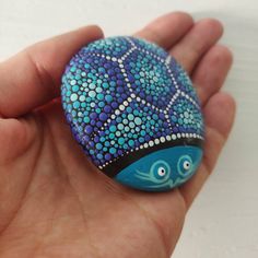 a hand holding a painted rock in it's palm