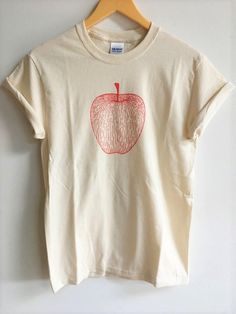 "Hand Printed and Hand Drawn! This is a 100% cotton screen printed t shirt with a hand drawn illustration of an apple. It's perfect for fall! The shirt shown here is Natural and printed in red ink. // PROCESS: All of our items are individually hand printed by either me or my dad, which can lead to slight variations in placement. The ink is heat cured and will not fade over time. Since our items are printed to order, there is a 1-2 week processing time before shipping. If you absolutely need an i Organic Short Sleeve T-shirt With Screen Print, Apple Shirt, Gardening Gift, Screen Printing Shirts, Foodie Gifts, Red Ink, Clothes Gift, Fashion Tees, Bristol