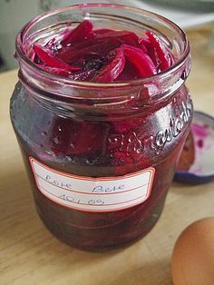 a jar filled with pickled beets next to an egg