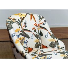 an upholstered chair with floral fabric on the back and arms, in front of a wood floor