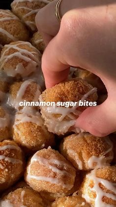 cinnamon sugar bites with icing on them in a bowl, being held up by someone's hand