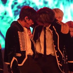 two young men dressed in black and white are kissing each other