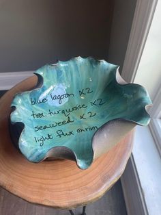 a blue bowl with writing on it sitting on top of a wooden table next to a window