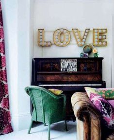 a living room filled with furniture and a love sign on the wall above a piano