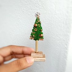 a hand holding a small wooden christmas tree