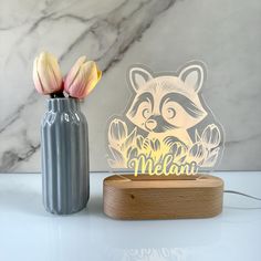 a raccoon lamp next to a vase with flowers