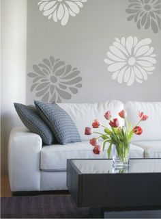 a white couch sitting in front of a wall with flowers on it's side