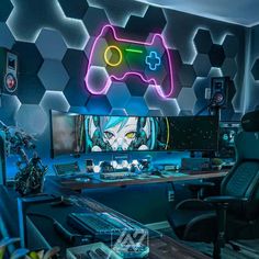 a computer desk with a gaming controller on top of it in front of a neon wall