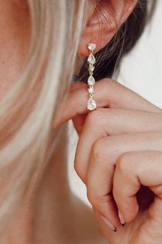 a close up of a person wearing a pair of ear clips and a ring on their left hand