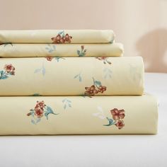 four sheets with floral designs on them are folded up and ready to be used as bed linens