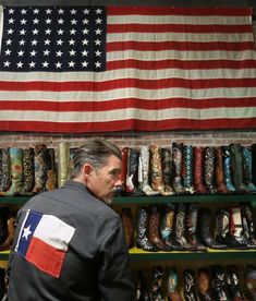 a man standing in front of an american flag next to a shelf with shoes on it