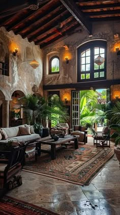 a living room filled with lots of furniture and plants on top of a rug covered floor