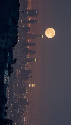 the full moon is seen in the sky over a city at night