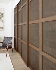 a chair sitting in front of a wall with wooden paneling on top of it