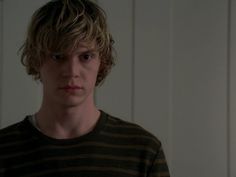 a young man standing in front of a mirror wearing a black and brown striped shirt