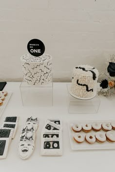 a table topped with cakes and donuts covered in frosting next to other desserts