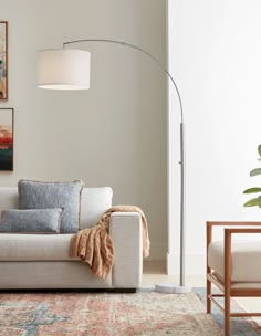 a living room with a couch, lamp and pictures hanging on the wall above it