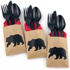 three black plastic utensils in a brown paper bag with bear silhouettes on them