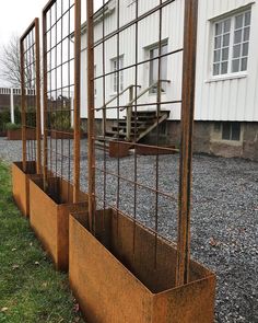 three metal planters sitting next to each other on top of a grass covered field