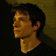 a close up of a person wearing a black shirt and looking off into the distance