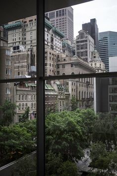 the view from an open window looking at buildings and trees