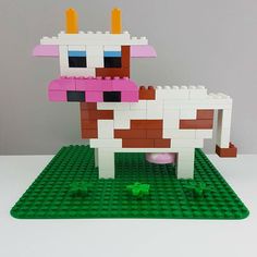 a toy cow made out of legos sitting on top of a green mat next to a gray wall