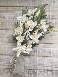 a bridal bouquet with white flowers and greenery on a wooden surface, ready to be used as a boutonniere