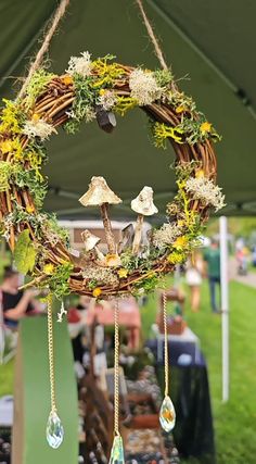 a wreath with mushrooms and plants hanging from it's sides in front of a tent