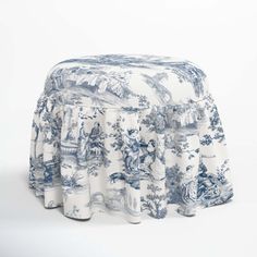 a blue and white toiler print tablecloth on top of a round ottoman