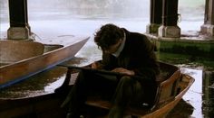 a man is sitting in a boat on the water while looking at his tablet computer