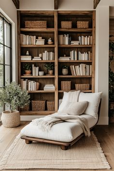 a white chaise lounge chair sitting in front of a bookshelf