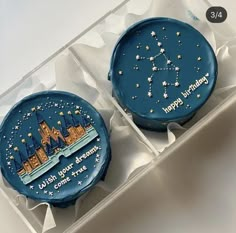 two decorated cupcakes in a box with writing on the frosting and stars