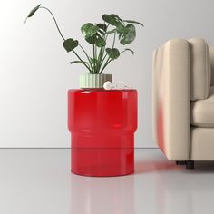 a red vase sitting on top of a table next to a white chair and couch