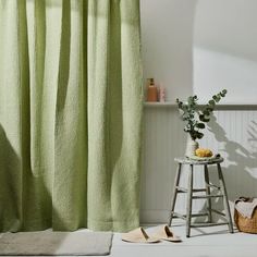 a green shower curtain next to a stool and potted plant