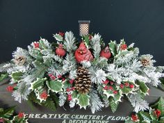 a christmas centerpiece with holly, pine cones and red cardinal bird on it's head