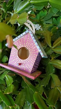 a pink birdhouse sitting on top of a lush green tree