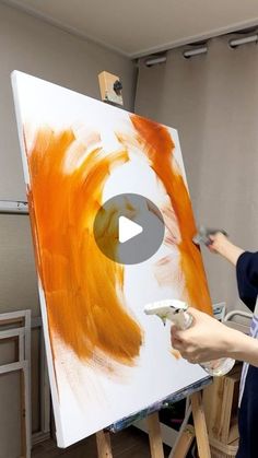 a woman is painting on an easel with orange paint