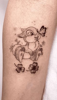 a small rabbit tattoo on the right thigh with clovers and butterflies around it,