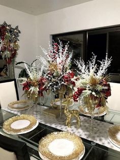 a glass table topped with plates and vases filled with flowers